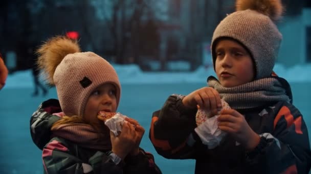 Дети едят пончики на открытом воздухе зимой — стоковое видео