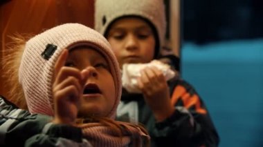 İki küçük çocuk dışarıda donut yiyor.