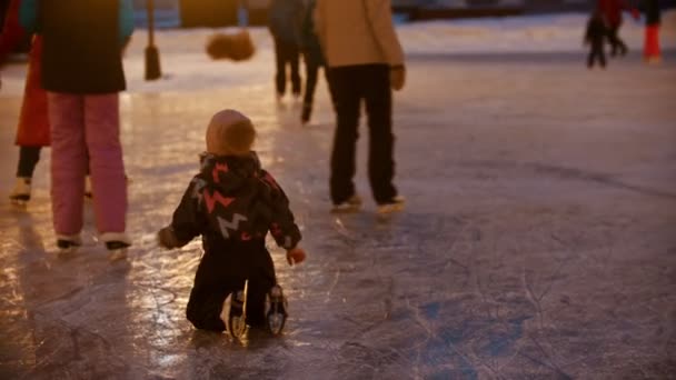 Malá holčička plazí na ledě - její matka a bratr bruslení k ní o pomoc — Stock video