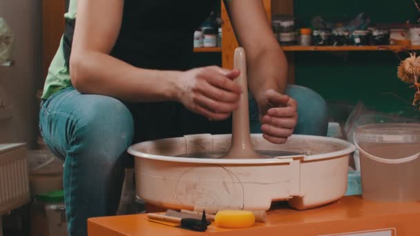 Een man nat zijn handen en blijven beeldhouwen van de figuur op aardewerk wiel — Stockvideo