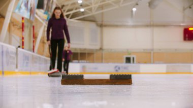 Spor kompleksinde körling antrenmanı. Arka planda kayan bir kadın.
