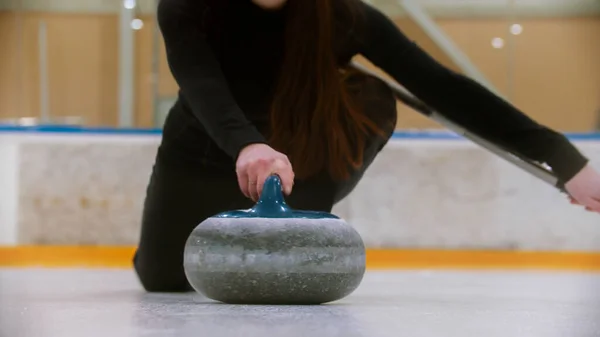 Curling - trzymanie granitowego kamienia z niebieskim uchwytem na polu lodowym — Zdjęcie stockowe