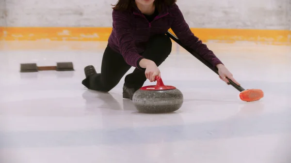 Curling training - vrouw schaatsen met een granieten steen met rode handvat — Stockfoto