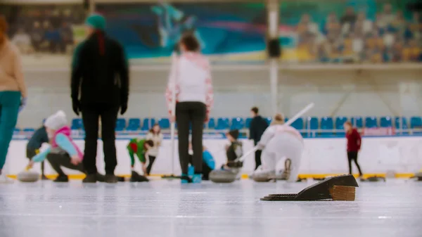 Curling training in the sport complex - different people training on the background