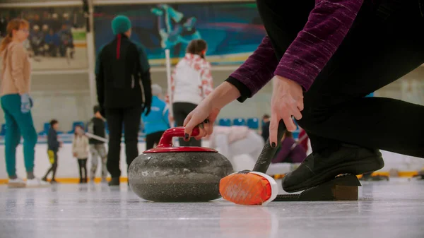 Curling - kvinna som håller i en granitsten med rött handtag och håller en speciell borste i en annan hand — Stockfoto