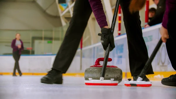 Curling entrenamiento - guiando piedra de granito en el hielo - limpiar el hielo antes de la piedra —  Fotos de Stock