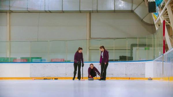 Curling training binnen - team van drie vrouwen die de granieten steen leiden — Stockfoto