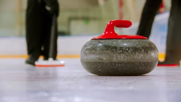 Curling-Training - ein Granitstein mit rotem Griff auf dem Eisfeld — Stockfoto