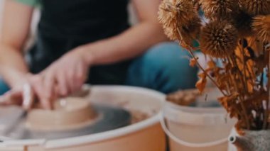 Çömlekçi adam atölyede kilden bir figürle çalışıyor.