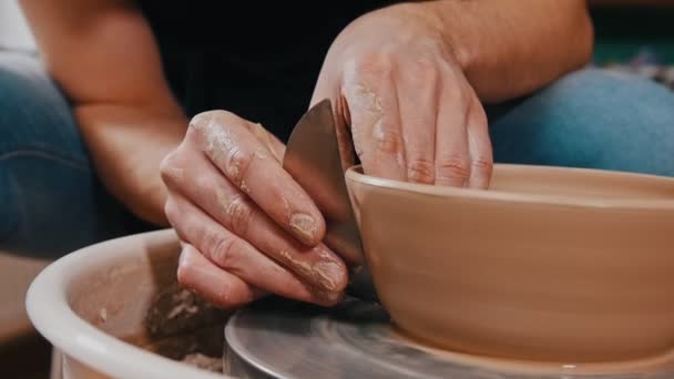 Человек гончар скульптуры горшок из глины вспомогательных с помощью лопатки - удаляет избыток по бокам — стоковое видео