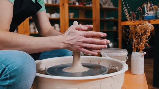 Pottery craftsmanship - a man forming piece of clay in longer shape spinning on a potters wheel — Stock Video