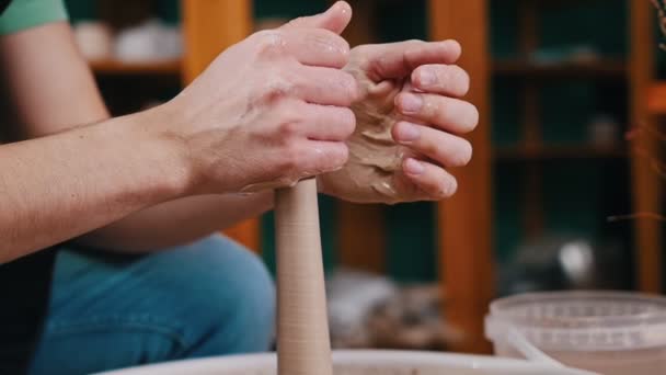 Een mensenhanden vormen stuk klei in langere vorm draaiend op een pottenbakkerswiel — Stockvideo