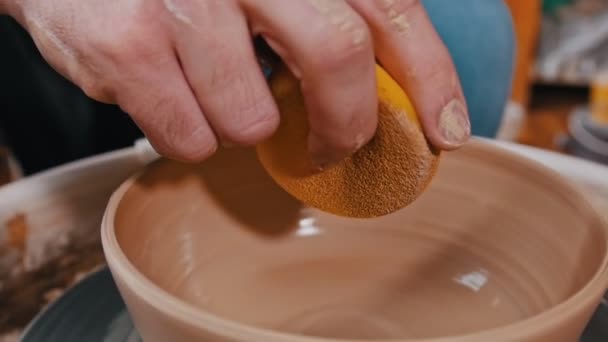Man pottenbakker werkt met een klei figuur met behulp van een spons - verwijdert restjes — Stockvideo