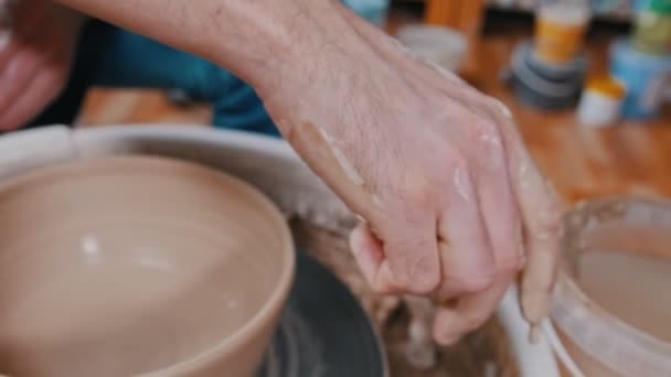 Człowiek garncarz pracujący z garnkiem za pomocą gąbki - usuwa resztki gliny — Wideo stockowe