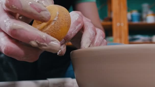 Man potter working with a pot using a sponge - removes leftovers from the top edges — 비디오