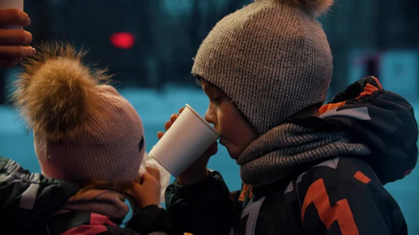 Een klein meisje en jongen die buiten warme dranken drinken — Stockfoto