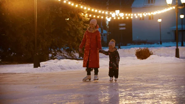 Een jonge vrouw schaatsen op de openbare ijsbaan met haar dochter — Stockfoto