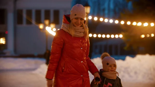 Een jonge glimlachende vrouw schaatsen op de openbare ijsbaan met haar dochter — Stockfoto
