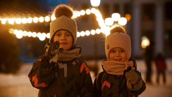 Twee kleine kinderen die op de openbare ijsbaan staan en in de camera kijken — Stockfoto