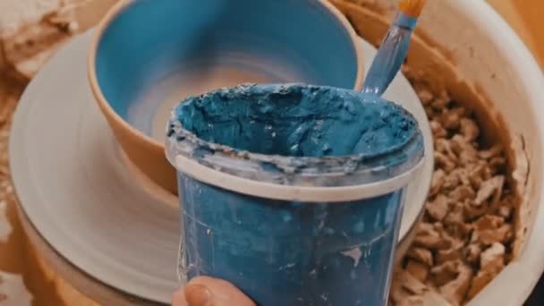 Pintar una olla de hilar al horno en color azul usando con un cepillo — Vídeos de Stock