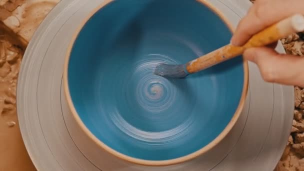 Måla en bakad spinnkruka i blått med hjälp av en pensel — Stockvideo