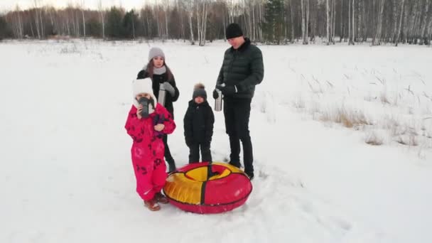 Famille debout au milieu du champ neigeux et ouvrant un thermos avec des boissons chaudes — Video