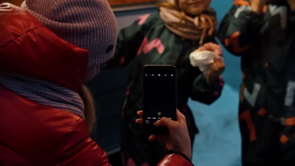 Een jonge vrouw die foto 's maakt van haar kinderen die warme dranken drinken en buiten donuts eten — Stockvideo