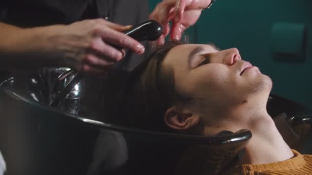 Мужчина, проходящий процедуру мойки волос в парикмахерской — стоковое видео
