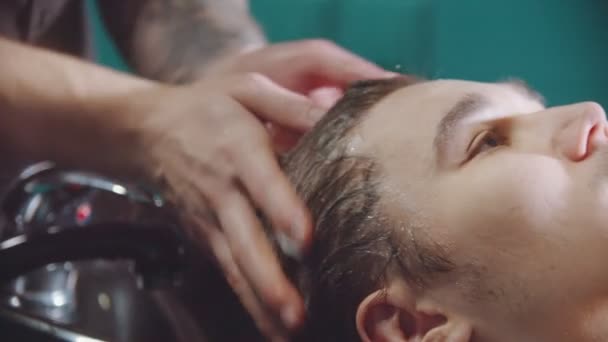 Um homem a lavar o cabelo com champô na barbearia — Vídeo de Stock