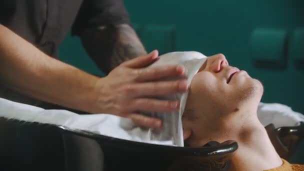 Чоловік перукар висушує волосся клієнта — стокове відео
