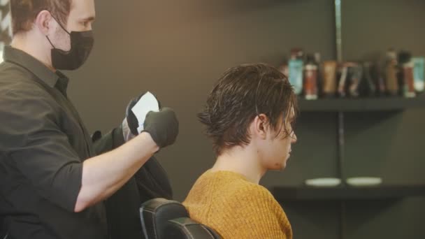 Barbier mettre une protection du cou sur son client dans le salon de coiffure — Video