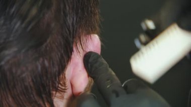 Berber genç adam kesiyor müşteriler ıslak saçlarını kulaklarının arkasına sokuyor.