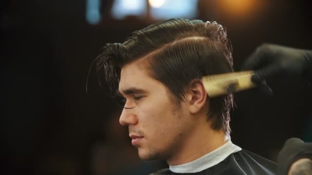 Молодой человек стрижется в парикмахерской — стоковое видео