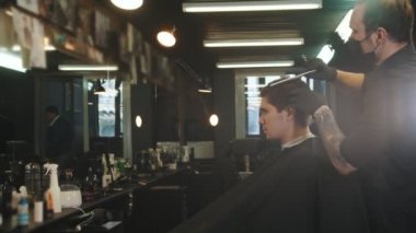 Modern berber dükkanında saç tıraşı olan yakışıklı bir genç.