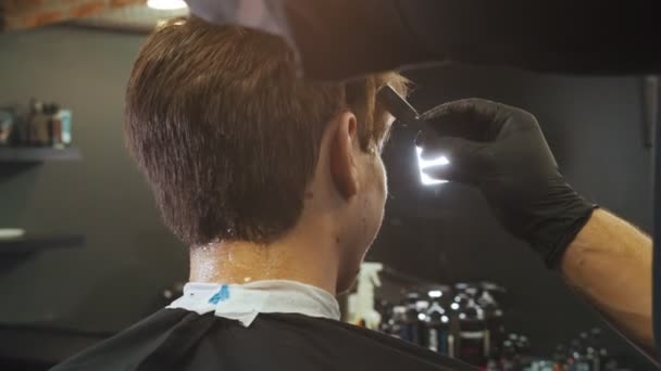 Um barbeiro homem fazendo toques de acabamento usando as lâminas nas bordas do cabelo — Vídeo de Stock