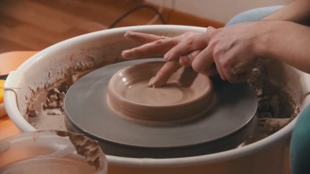 Керамика - мастер с пальцем делает дно для глиняной чаши на гончарном круге — стоковое видео