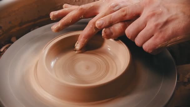 Aardewerk - man met vinger maakt de bodem voor een klei kom op het pottenbakkerswiel — Stockvideo