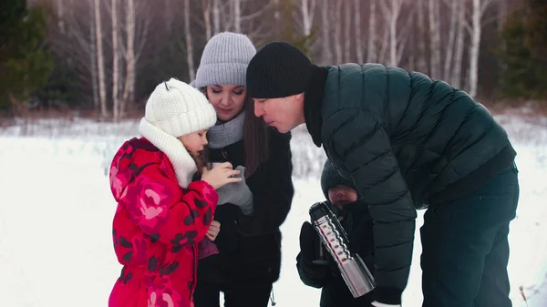 Familie die 's winters buiten staat - warme dranken uit de thermoskan drinken — Stockfoto