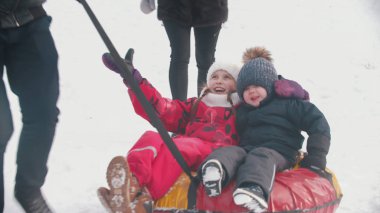Family playing outdoors - riding kids on the inflatable boat