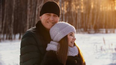 A married smiling couple hugging at winter near the forest