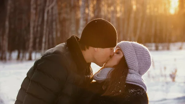 Um casal se beija ao ar livre no inverno perto da floresta — Fotografia de Stock