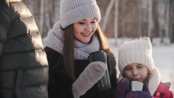 Smiling woman drinking hot drink with her daughter — Stockfoto