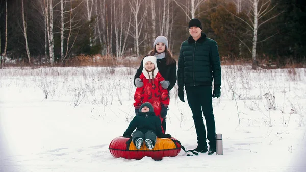 Family standing outdoors near winter forest and looking in the camera — Stockfoto