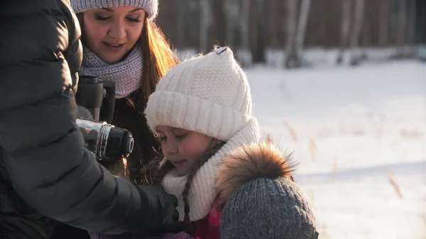 Young parents pouring hot drink in the cup for their daughter — Stockfoto