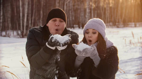 A married couple blowing out snow from their hands — 스톡 사진