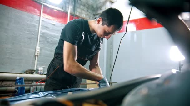 Servicio de reparación de coches - hombre que trabaja con el coche bajo el capó abierto del coche — Vídeo de stock