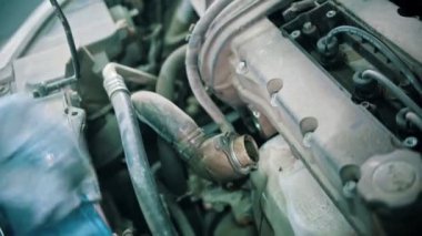 Kapalı alanda araba tamirciliği yapan adam termostat tamiri yapıyor.