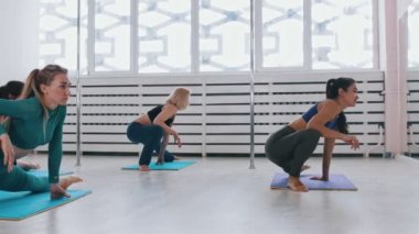 Yoga minderinde bacaklarını esneten genç kadınlar.