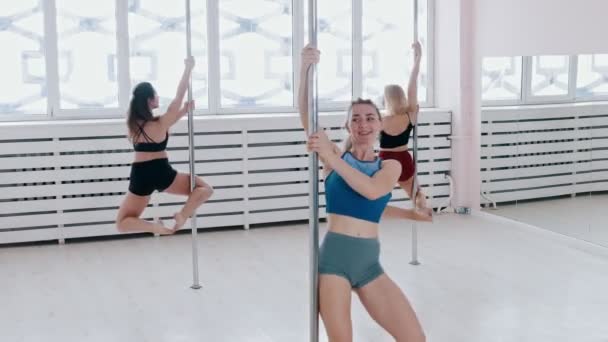 Mujeres jóvenes entrenando pole bailando en el luminoso estudio — Vídeos de Stock