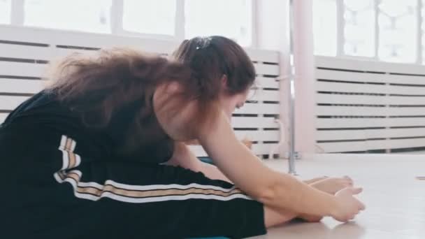 Mujeres jóvenes entrenando en la esterilla de yoga - agacharse hasta los dedos de los pies — Vídeos de Stock